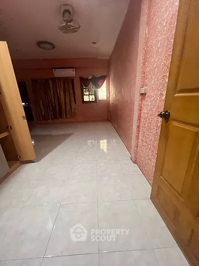 Spacious room with tiled flooring and vibrant pink walls, featuring a ceiling fan and air conditioning unit.