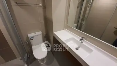 Modern bathroom with sleek fixtures and spacious shower area in a contemporary apartment.
