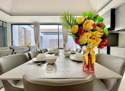 Modern dining area with elegant table setting and vibrant floral centerpiece in a stylish open-plan living space.