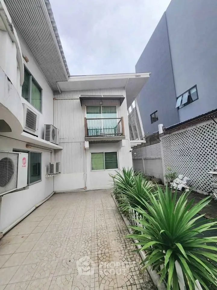 Modern two-story building with tiled courtyard and lush greenery, perfect for urban living.