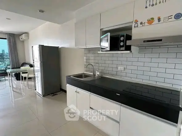 Modern kitchen with sleek cabinetry and dining area in open layout apartment.