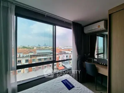 Modern bedroom with large window offering stunning city view and natural light.