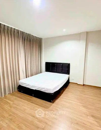Spacious bedroom with wooden flooring and elegant curtains