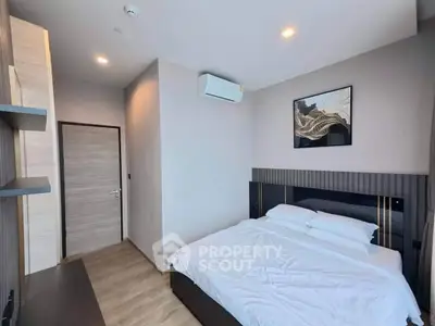 Modern bedroom with sleek design, featuring a comfortable bed, stylish artwork, and ambient lighting.
