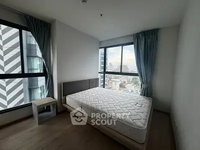 Modern bedroom with large windows and city view in high-rise apartment