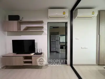 Modern living room with sleek wooden furniture and mirrored wall, featuring air conditioning and open kitchen view.