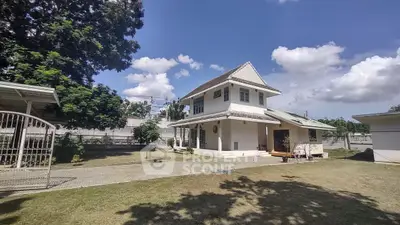 Charming two-story house with spacious yard and lush greenery under a clear blue sky.