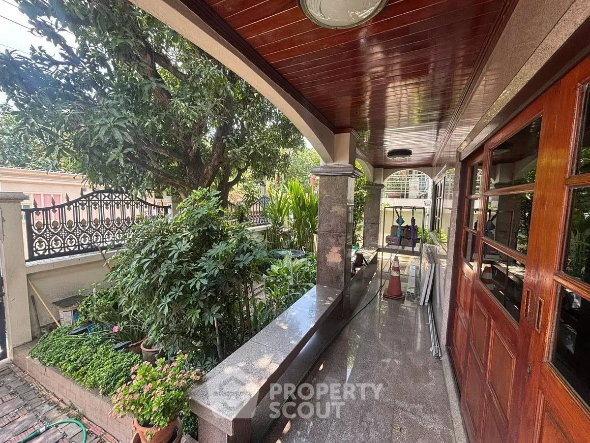 Charming outdoor patio with lush greenery and elegant wooden accents, perfect for relaxation and entertaining.
