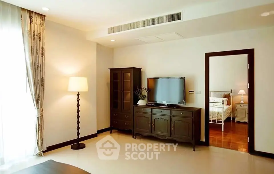 Elegant living room with stylish furniture and a glimpse of a cozy bedroom
