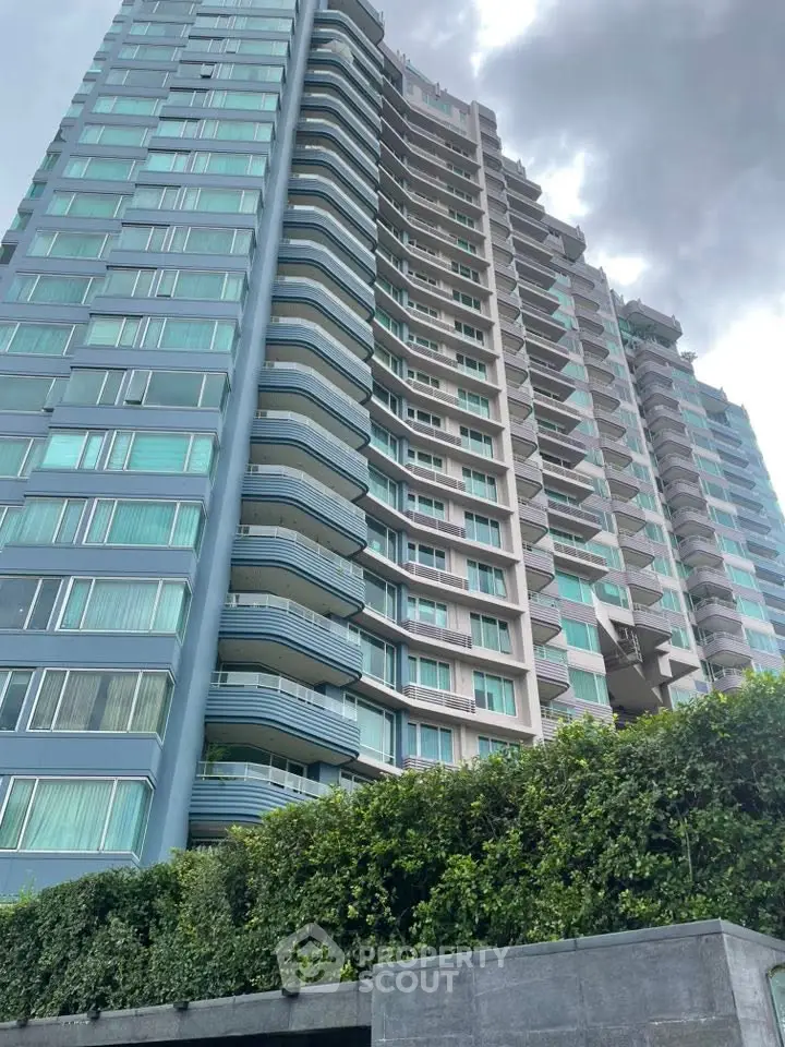 Stunning high-rise building with modern architecture and lush greenery at the base.