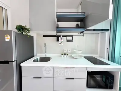 Modern kitchen with sleek cabinets, induction cooktop, and stainless steel appliances in a stylish apartment.
