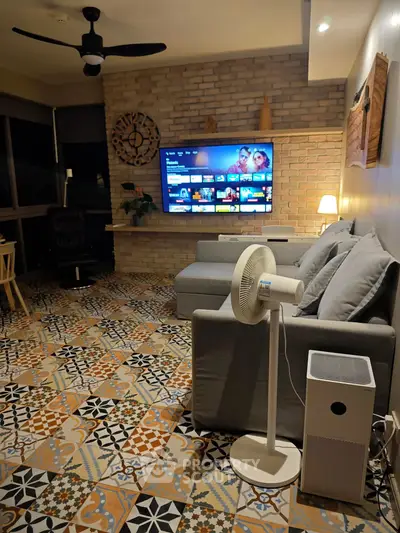 Stylish living room with modern decor and large TV, featuring patterned tile flooring and cozy seating.