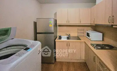 Modern kitchen with appliances including fridge, microwave, and washing machine in compact layout.