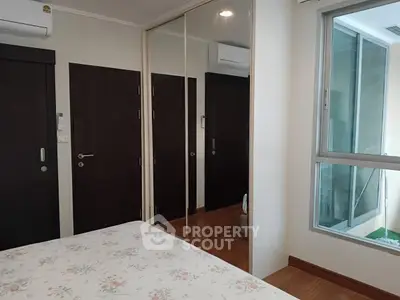 Cozy bedroom with mirrored closet and large window for natural light