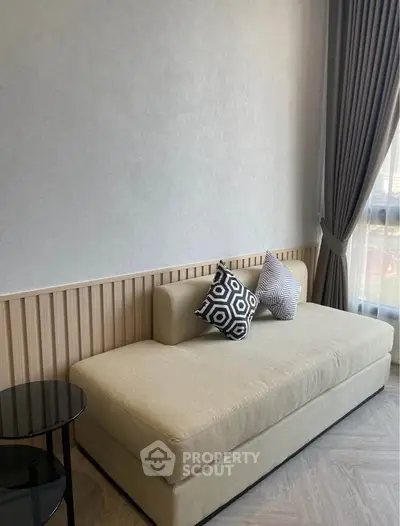 Modern living room with stylish sofa and decorative pillows, featuring elegant curtains and natural light.