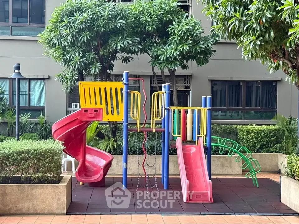 Charming residential playground with vibrant slides and lush greenery, perfect for family-friendly living.