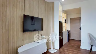 Modern living room with sleek TV and stylish wooden paneling, open kitchen layout, and elegant flooring.
