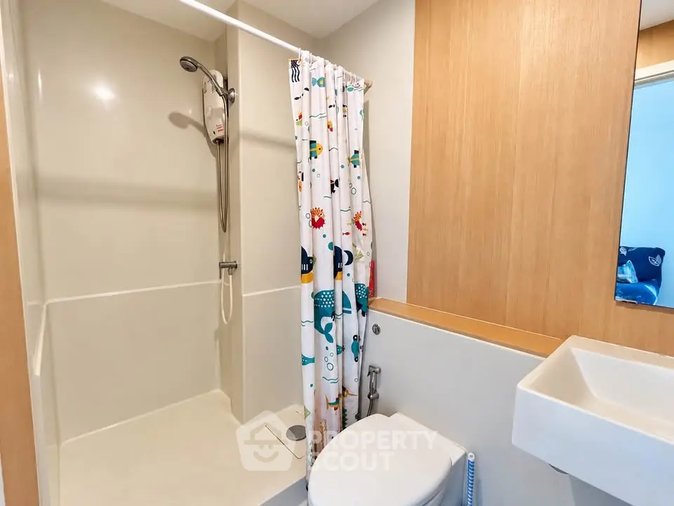 Modern bathroom with shower and colorful curtain in cozy apartment.