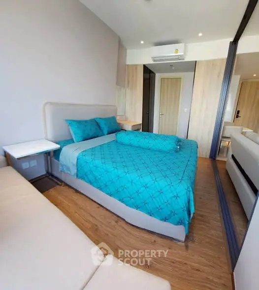 Modern bedroom with turquoise bedding and mirrored wardrobe in stylish apartment.