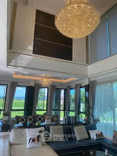 Luxurious living room with high ceilings, elegant chandeliers, and expansive windows offering stunning views.