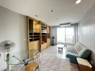 Bright living room with modern furniture and large window leading to balcony.