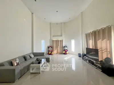 Spacious living room with high ceilings and modern decor, featuring a large sectional sofa and entertainment center.