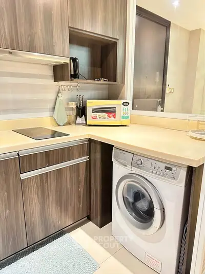 Modern kitchen with built-in washing machine and sleek wooden cabinets