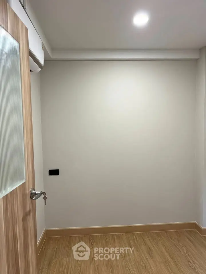 Minimalist empty room with wooden flooring and modern door, perfect for customization.