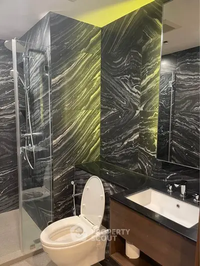 Luxurious modern bathroom with sleek black marble walls and glass shower enclosure.