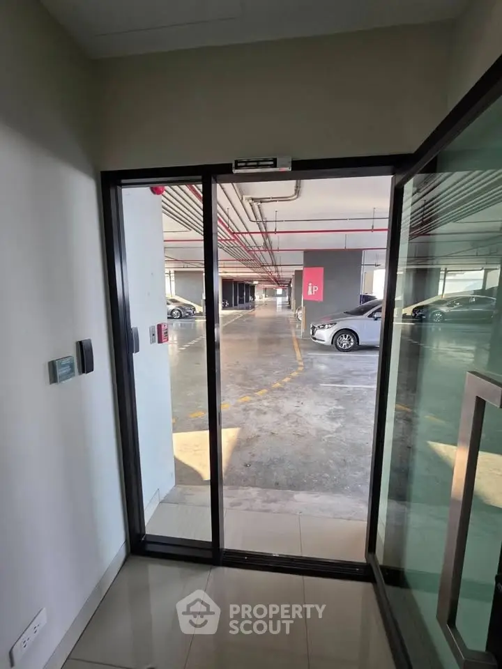 Modern parking garage entrance with glass doors and visible parking spaces.
