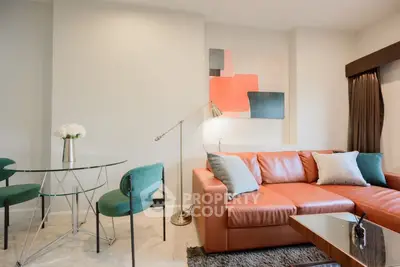 Modern living room with stylish decor, featuring a leather sofa, glass table, and contemporary art.