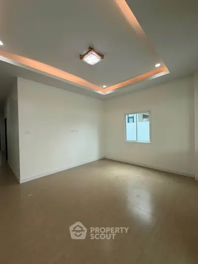 Spacious empty room with modern ceiling lights and natural light from window