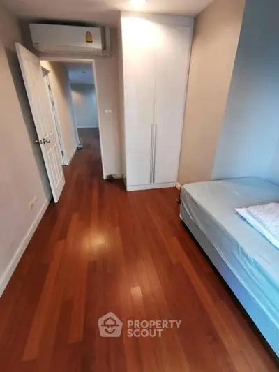 Cozy bedroom with wooden flooring and built-in wardrobe, perfect for modern living.