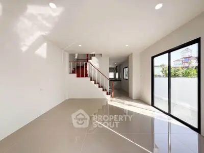 Spacious modern living room with sleek staircase and large windows for natural light.