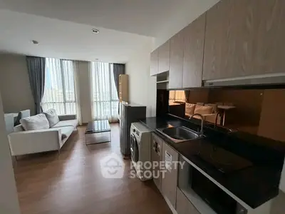 Modern open-layout kitchen and living room with natural light and stylish furnishings.
