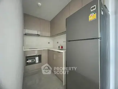 Modern compact kitchen with sleek cabinetry and stainless steel fridge