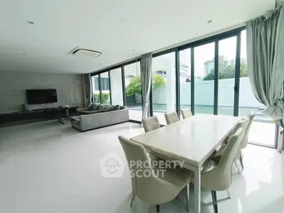 Spacious modern living room with large windows and elegant dining area