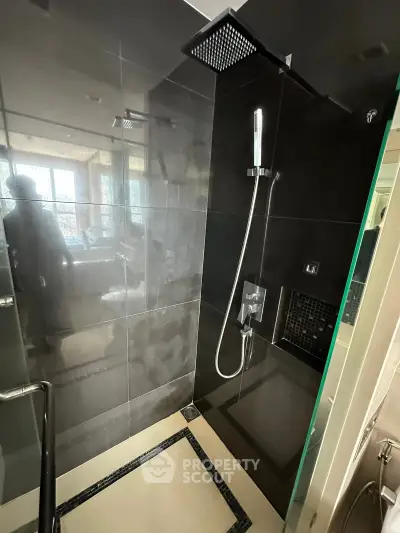 Modern bathroom with sleek black tiles and a rainfall showerhead