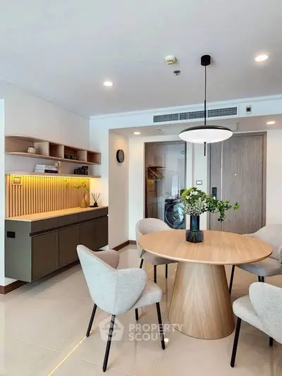 Modern dining area with stylish round table, elegant chairs, and built-in storage in a contemporary apartment.
