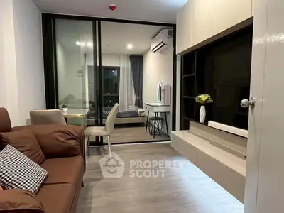 Modern apartment interior with stylish living room and cozy bedroom separated by glass doors.