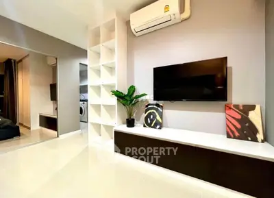 Modern living room with sleek TV setup and air conditioning, featuring stylish decor and ample storage.