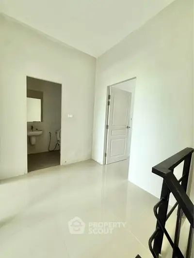 Bright hallway with modern bathroom entrance and sleek railing design