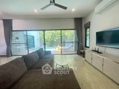 Spacious living room with pool view, modern furniture, and large sliding glass doors for natural light.