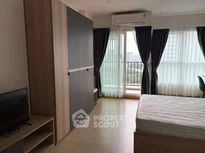 Modern bedroom with balcony and city view, featuring sleek furniture and natural light.