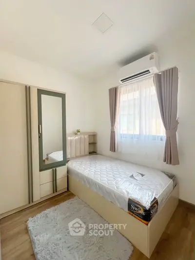 Cozy bedroom with single bed, air conditioning, and ample storage in modern apartment.