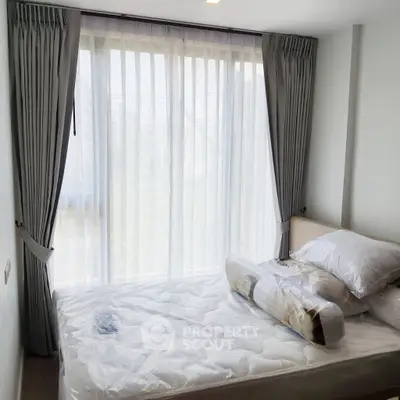 Bright bedroom with large window and elegant curtains, showcasing a cozy and inviting atmosphere.