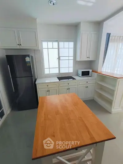 Modern kitchen with wooden island, sleek appliances, and ample storage space.