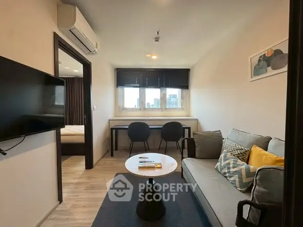 Modern living room with stylish decor and city view, featuring cozy seating and wall-mounted TV.