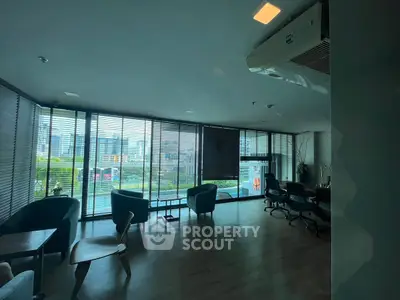Spacious living room with modern furniture and city view through large windows.