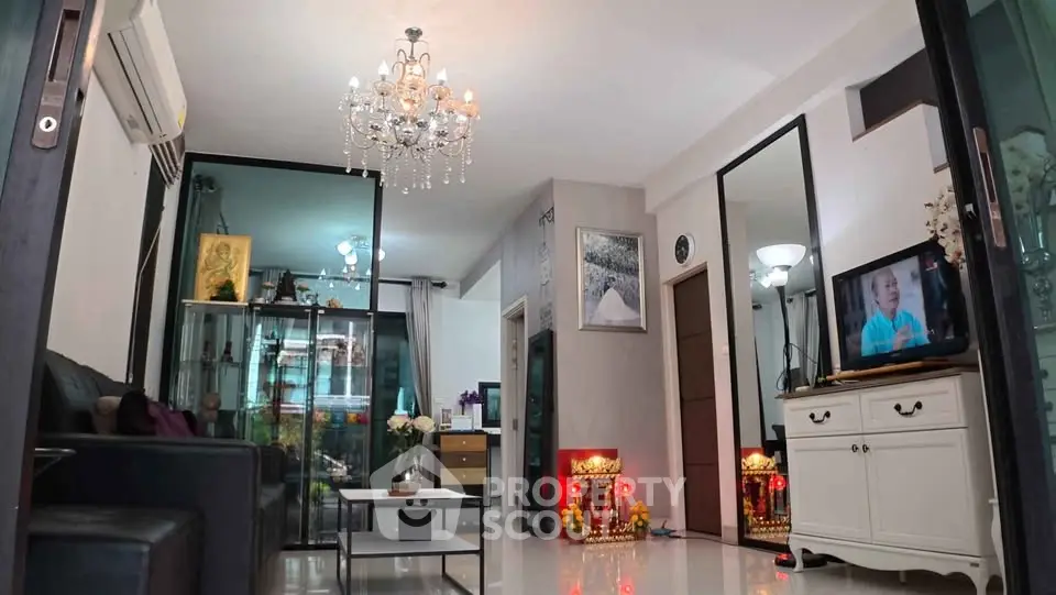 Elegant living room with chandelier and modern decor, featuring a cozy seating area and stylish furniture.